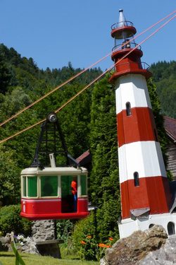 Gondel mit Leuchtturm. Focus sowohl auf der Gondel wie auf dem Leuchtturm. (Windbewegung sichtbar am Tragseil)