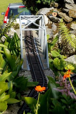 Bahnbrücke mit Blume im Vordergrund. Alle Bildteile sind fucusiert (leichte Aura bei der Blume)